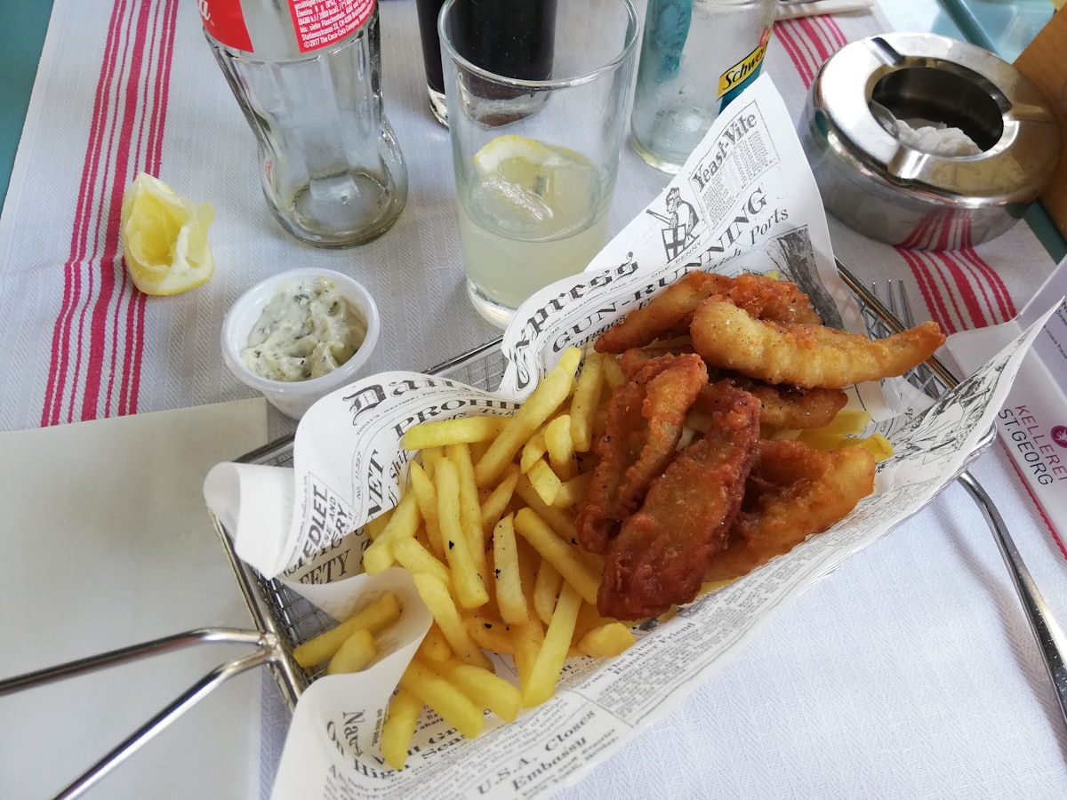Battered fish and chips served in newspaper, with tartare sauce and a wedge of lemon
